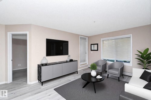 Living area featuring light-toned walls, wood-finish flooring, and a large window with horizontal blinds - 108 530 Watt Boulevard, Edmonton, AB 