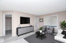 Living area featuring light-toned walls, wood-finish flooring, and a large window with horizontal blinds - 108 530 Watt Boulevard, Edmonton, AB 