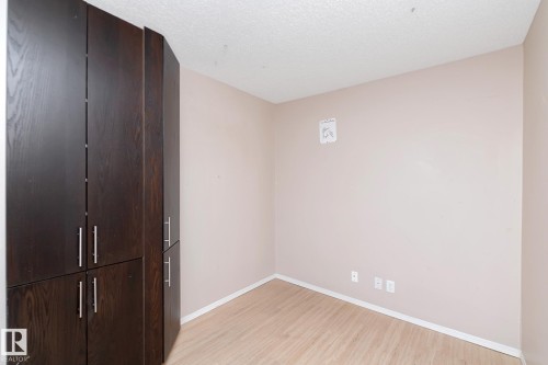 Built-in dark wood-finish cabinetry with brushed nickel hardware, light wood-finish flooring, and neutral wall paint - 108 530 Watt Boulevard, Edmonton, AB 