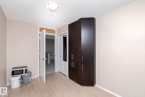 Corner built-in cabinetry with dark wood-finish, light wood-finish flooring, and white interior doors - 108 530 Watt Boulevard, Edmonton, AB 