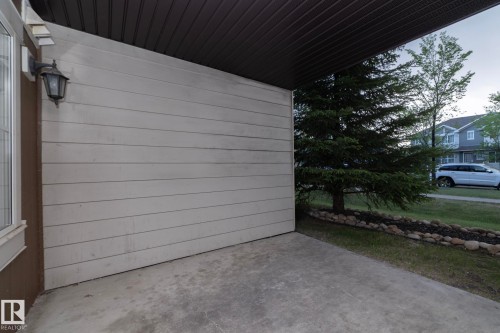 Concrete patio area featuring a mounted exterior light fixture and light-toned horizontal siding - 108 530 Watt Boulevard, Edmonton, AB 