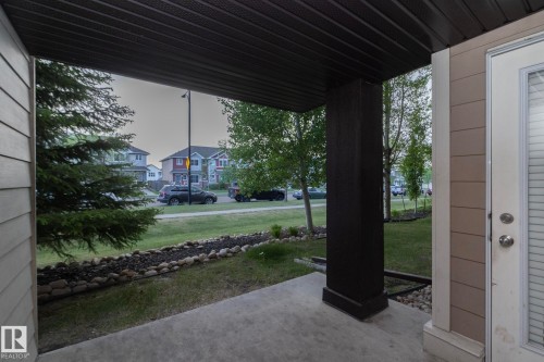 Covered concrete patio featuring a dark brown support column and a white door with integrated blinds - 108 530 Watt Boulevard, Edmonton, AB 