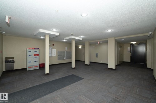 Spacious common area featuring textured tile flooring, recessed lighting, individual mailboxes, and parcel lockers - 108 530 Watt Boulevard, Edmonton, AB 