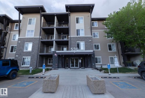 Modern multi-story building featuring a facade of horizontal siding and stacked stone accents - 108 530 Watt Boulevard, Edmonton, AB 