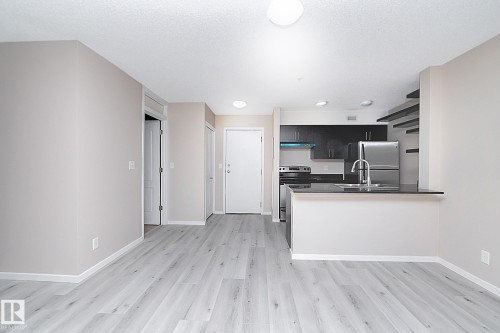 Open-concept living area with light-toned wood-finish flooring - 108 530 Watt Boulevard, Edmonton, AB 