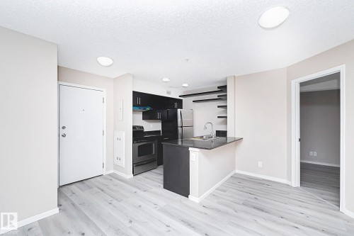 Open-concept living area featuring contemporary wood-finish flooring - 108 530 Watt Boulevard, Edmonton, AB 
