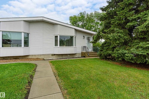White siding exterior featuring multiple bay windows and a concrete pathway leading to the entry - 9011 60 Street, Edmonton, AB 
