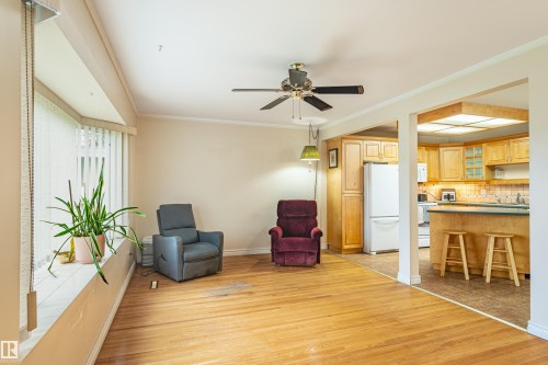 Hardwood flooring throughout a spacious room with a bay window, ceiling fan, and crown molding - 9011 60 Street, Edmonton, AB 