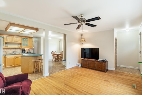 Bright living space featuring hardwood flooring, a ceiling fan, and crown molding - 9011 60 Street, Edmonton, AB 