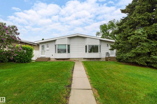 Split-level residence featuring light-colored siding, a front walkway, and a manicured lawn - 9011 60 Street, Edmonton, AB 