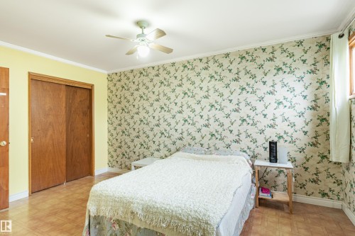 Room featuring wood-finish flooring, a ceiling fan with light fixture, and a window providing natural light - 9011 60 Street, Edmonton, AB 