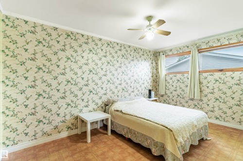 Room featuring floral wallpaper, wood-finish flooring, and white baseboards - 9011 60 Street, Edmonton, AB 