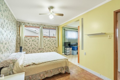 Bedroom featuring a ceiling fan, multiple windows, and patterned wallpaper - 9011 60 Street, Edmonton, AB 