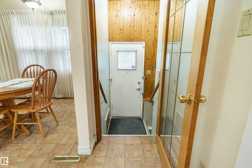 Entryway featuring wood paneling and a glass-paneled interior door - 9011 60 Street, Edmonton, AB 