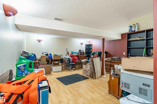 Spacious room featuring wood-finish flooring, a textured ceiling, and recessed wall sconces - 9011 60 Street, Edmonton, AB 