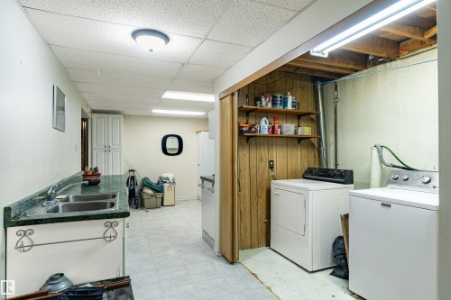 Utility area featuring a double basin sink, green countertop, and built-in white cabinetry - 9011 60 Street, Edmonton, AB 