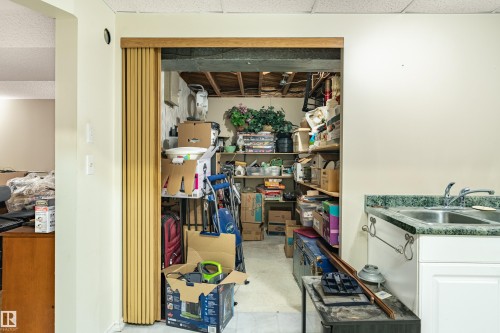 Utility room with built-in shelving, a double basin sink, and a decorative laminate countertop - 9011 60 Street, Edmonton, AB 