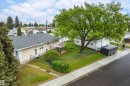 Expansive rear yard featuring a wooden deck, mature shade tree, and detached garage with dual doors - 9011 60 Street, Edmonton, AB 