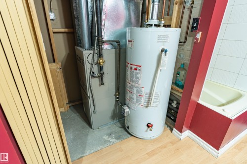 Utility area featuring a water heater, furnace, and wood-finish flooring - 9011 60 Street, Edmonton, AB 