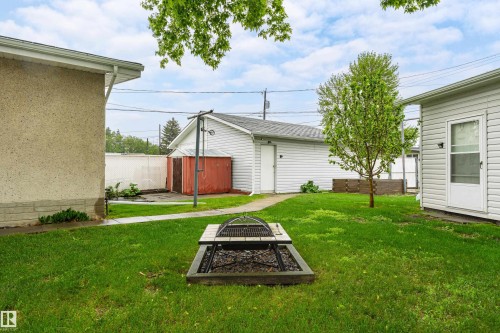 Manicured lawn featuring a built-in fire pit with an integrated grill, a paved walkway, and mature landscaping - 9011 60 Street, Edmonton, AB 