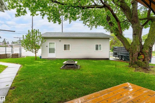 Expansive green lawn featuring a dedicated fire pit area - 9011 60 Street, Edmonton, AB 