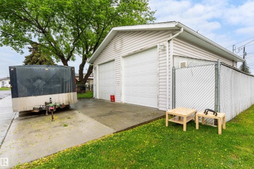 Two-stall garage featuring white panel garage doors, light-colored siding, and a concrete driveway - 9011 60 Street, Edmonton, AB 