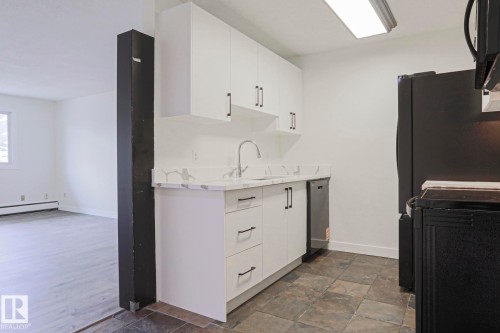 Kitchen featuring white cabinetry, a stainless steel sink with a gooseneck faucet, a dishwasher, and black appliances - 205 14903 92 Avenue Nw, Edmonton, AB 