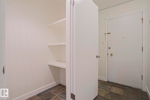 Built-in shelving for organized storage, complemented by a slate-style tile floor and a solid white entry door - 205 14903 92 Avenue Nw, Edmonton, AB 