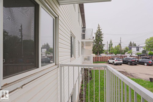 Exterior balcony featuring white metal railings, white vinyl siding, and multiple windows - 205 14903 92 Avenue Nw, Edmonton, AB 