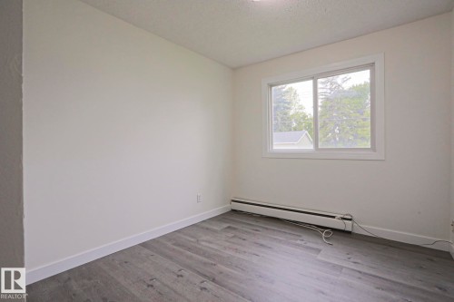 Bright room featuring a large window, neutral wall paint, and wood-finish flooring - 205 14903 92 Avenue Nw, Edmonton, AB 