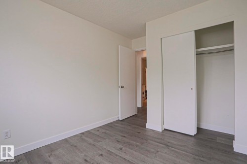 Neutral-toned interior featuring wood-finish flooring, white baseboards, and a closet with sliding doors - 205 14903 92 Avenue Nw, Edmonton, AB 