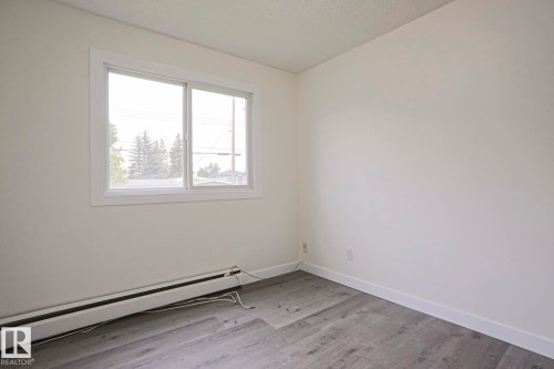 Room featuring a single window with white trim, wood-finish flooring, and white baseboard trim - 205 14903 92 Avenue Nw, Edmonton, AB 