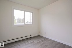 Room featuring a single window with white trim, wood-finish flooring, and white baseboard trim - 