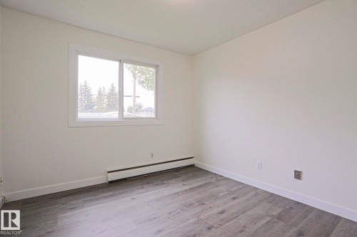 Interior room featuring light gray wood-finish flooring, white baseboards, and neutral wall tones - 205 14903 92 Avenue Nw, Edmonton, AB 