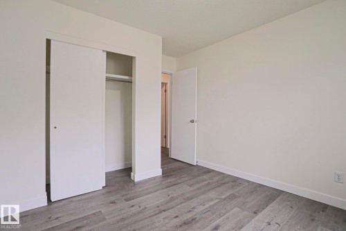 Room featuring wood-finish flooring, white walls, and a built-in closet with sliding doors - 205 14903 92 Avenue Nw, Edmonton, AB 