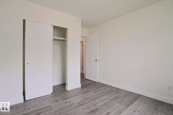 Room featuring wood-finish flooring, white walls, and a built-in closet with sliding doors - 