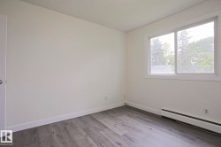 Bright room featuring light gray wood-finish flooring, white baseboards, and a large sliding window - 