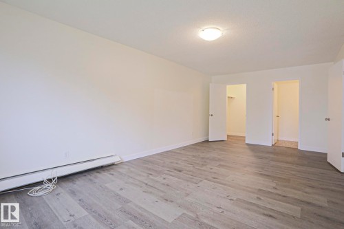 Spacious room featuring light wood-finish flooring, white baseboards, and a neutral wall color - 205 14903 92 Avenue Nw, Edmonton, AB 