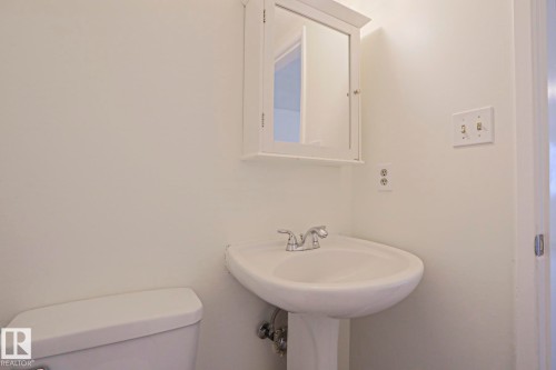 Pedestal sink with chrome-finish faucet, white medicine cabinet, and white walls - 205 14903 92 Avenue Nw, Edmonton, AB 