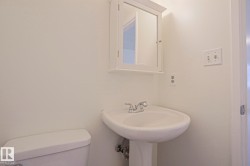Pedestal sink with chrome-finish faucet, white medicine cabinet, and white walls - 