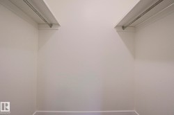 Spacious closet featuring white walls, shelving, and metal hanging rods - 