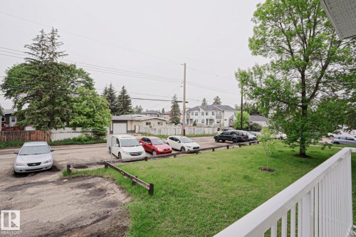 Expansive green lawn with mature trees and a partial white picket fence - 205 14903 92 Avenue Nw, Edmonton, AB 
