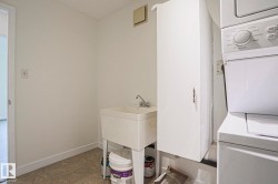 Laundry area featuring a utility sink, wall-mounted cabinetry, and stacked washer and dryer - 