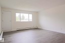 Spacious interior featuring light gray wood-finish flooring, white baseboards, and a neutral color palette throughout - 205 14903 92 Avenue Nw, Edmonton, AB 