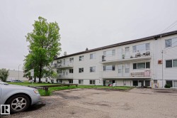 Multi-story building featuring white horizontal siding and multiple private balconies - 