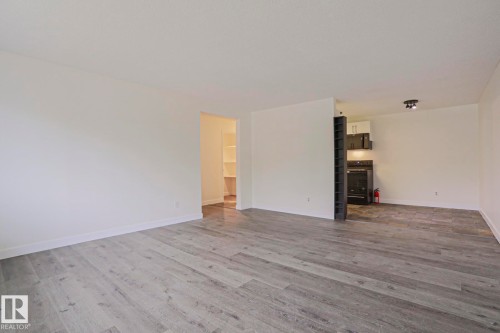 Spacious interior featuring wood-finish flooring, white baseboards, and a neutral wall palette - 205 14903 92 Avenue Nw, Edmonton, AB 