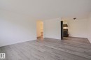Spacious interior featuring wood-finish flooring, white baseboards, and a neutral wall palette - 205 14903 92 Avenue Nw, Edmonton, AB 