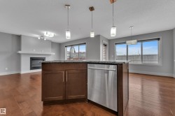 Central kitchen island featuring dark wood cabinetry, a granite-finish countertop, and an integrated stainless steel dishwasher - 