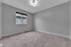 Neutral-toned carpeting complements light gray wall paint in this room featuring a single window with a black roller blind - 