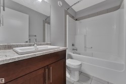 Bathroom featuring a vanity with a white rectangular undermount sink, a chrome faucet, and a light-colored speckled countertop - 